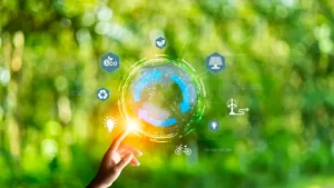 Mão segurando uma esfera holográfica com ícones de sustentabilidade, energia, reciclagem e internet das coisas sobre fundo verde desfocado, simbolizando tecnologia verde e economia circular.